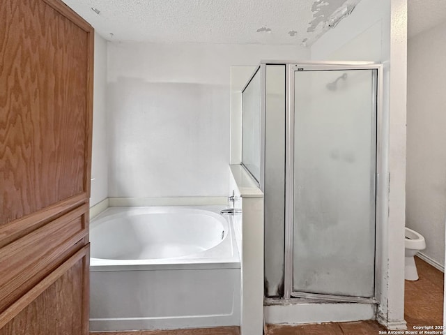 bathroom featuring separate shower and tub and a textured ceiling