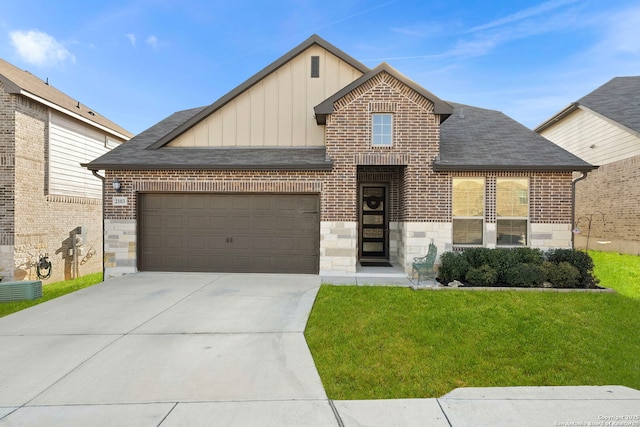 view of front facade featuring concrete driveway, an attached garage, board and batten siding, a front yard, and stone siding