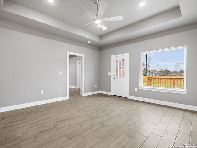 spare room featuring a raised ceiling, light hardwood / wood-style flooring, and ceiling fan