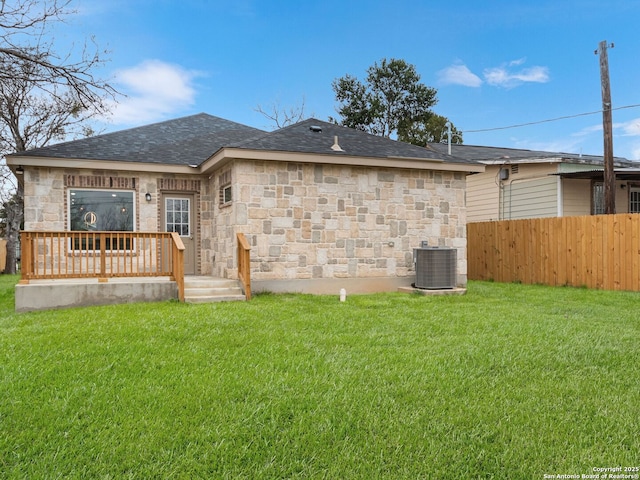 rear view of house with central AC and a lawn