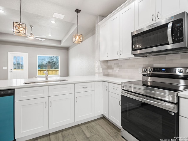 kitchen featuring appliances with stainless steel finishes, decorative light fixtures, sink, and white cabinetry