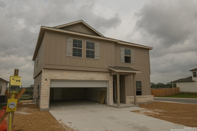 view of front of property featuring board and batten siding, stone siding, a garage, fence, and concrete driveway