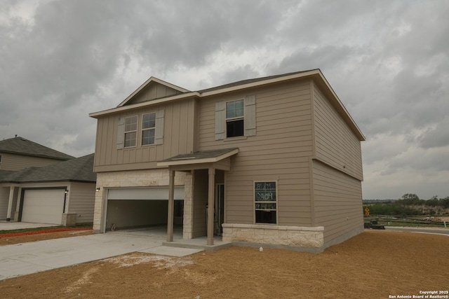 view of front facade featuring stone siding, an attached garage, concrete driveway, and board and batten siding