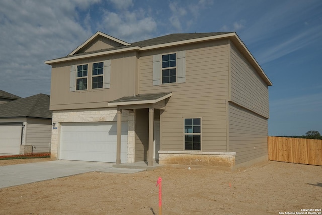view of front of property with fence, an attached garage, concrete driveway, and stone siding