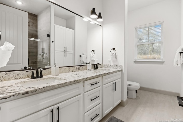 bathroom featuring vanity, a shower with door, and toilet