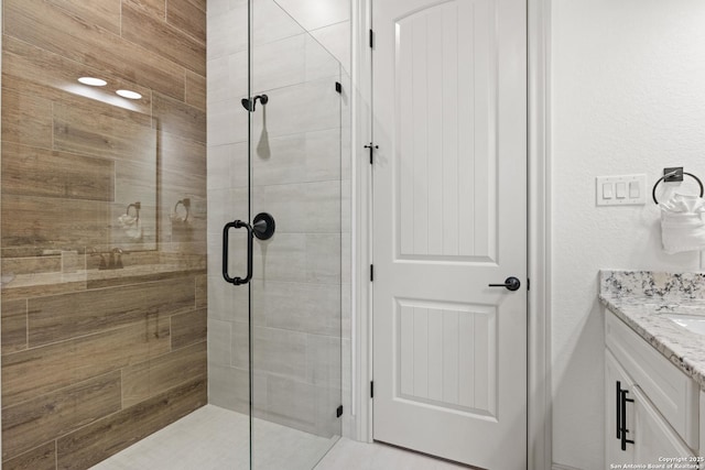 bathroom with a shower with shower door and vanity