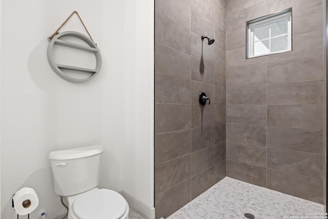 bathroom with a tile shower and toilet