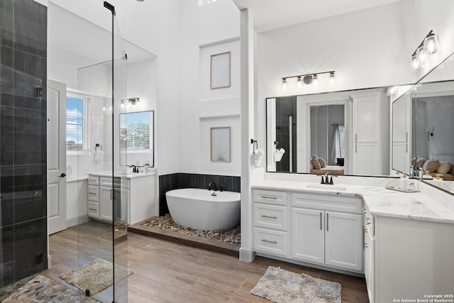 bathroom with hardwood / wood-style flooring, vanity, and plus walk in shower