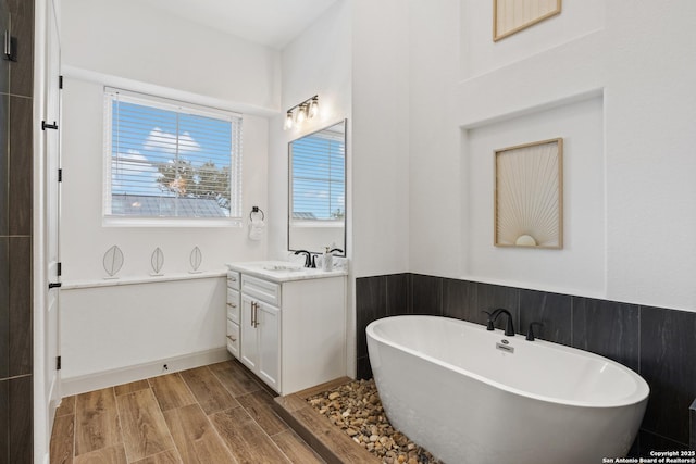 bathroom with hardwood / wood-style flooring, vanity, and a bath