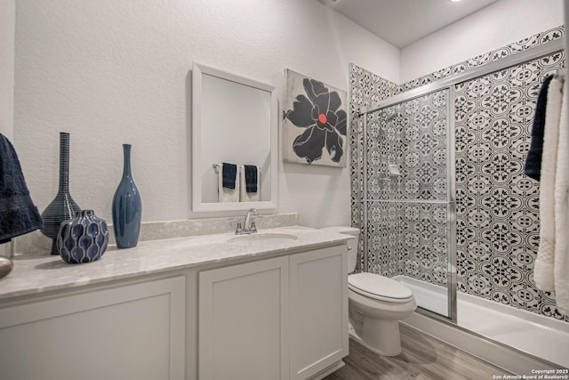 bathroom featuring vanity, toilet, a shower with shower door, and hardwood / wood-style floors