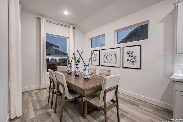 dining area featuring light wood-type flooring and vaulted ceiling