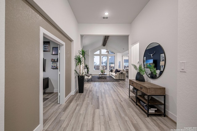 hallway featuring light hardwood / wood-style flooring and vaulted ceiling with beams