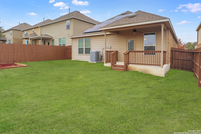 back of property with a lawn, solar panels, a wooden deck, and central AC