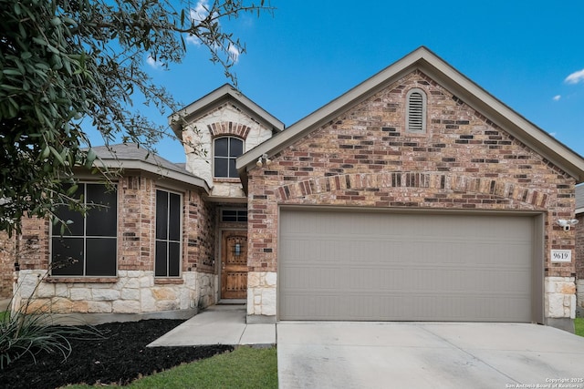 view of front of home featuring an attached garage, stone siding, and driveway