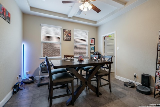 dining space featuring a raised ceiling, ceiling fan, and baseboards