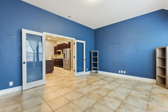 empty room featuring light tile patterned floors, french doors, visible vents, and baseboards