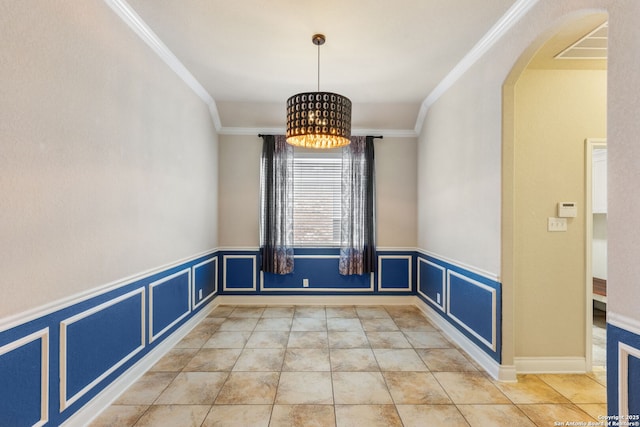 unfurnished dining area featuring a wainscoted wall, arched walkways, a decorative wall, and ornamental molding