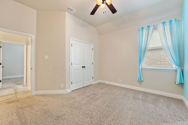 unfurnished bedroom featuring lofted ceiling, visible vents, baseboards, a closet, and carpet