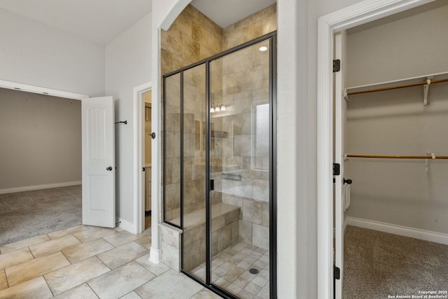 bathroom featuring a stall shower, a spacious closet, and baseboards