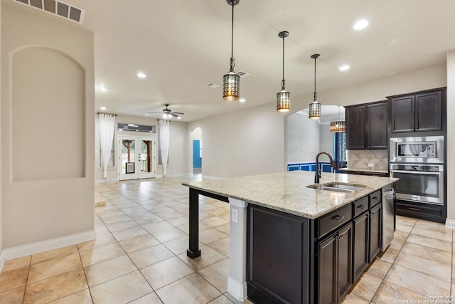 kitchen with arched walkways, stainless steel appliances, tasteful backsplash, visible vents, and a sink