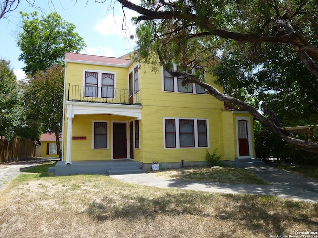 view of front of home featuring a balcony and a front yard