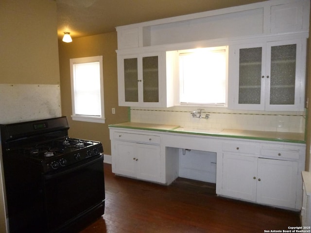 kitchen with tasteful backsplash, white cabinets, black gas stove, dark hardwood / wood-style flooring, and sink