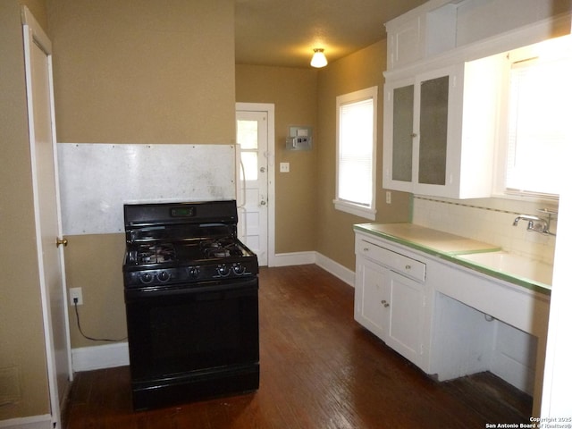 kitchen with gas stove, sink, white cabinetry, dark wood-type flooring, and decorative backsplash