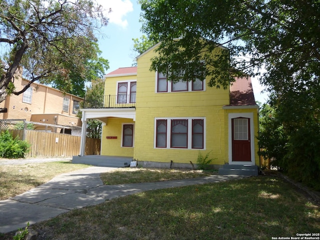 view of front facade with a balcony and a front yard