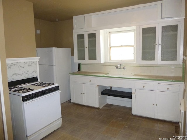 kitchen with sink, tasteful backsplash, white gas stove, and white cabinets