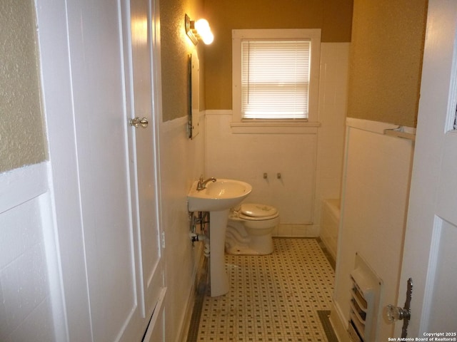 bathroom featuring toilet and a washtub