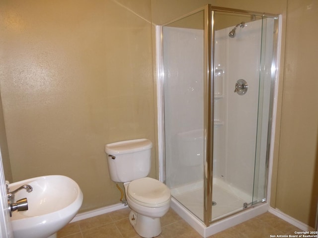 bathroom with sink, tile patterned flooring, a shower with door, and toilet