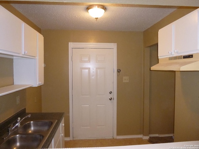 kitchen featuring white cabinets, sink, and a textured ceiling