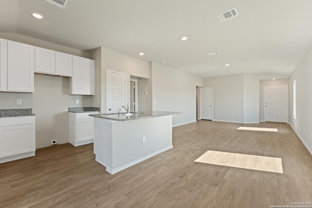 1836 Charlie Cv, San Antonio, TX 78221 - kitchen featuring light wood-type flooring, a kitchen island with sink, white cabinets, and stone countertops
