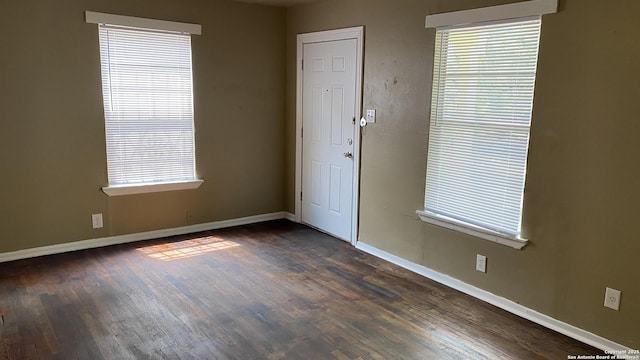 spare room featuring dark wood-type flooring and plenty of natural light