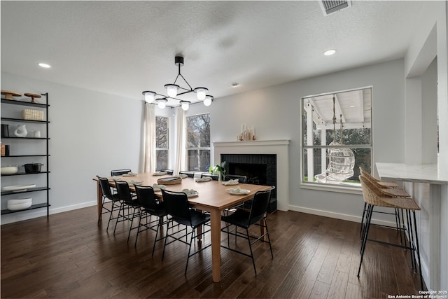 dining space featuring dark hardwood / wood-style flooring, plenty of natural light, an inviting chandelier, and a textured ceiling