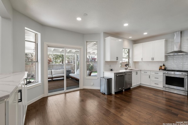 kitchen featuring wall chimney exhaust hood, stainless steel appliances, and white cabinetry