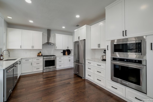 kitchen with dark hardwood / wood-style flooring, sink, appliances with stainless steel finishes, white cabinets, and wall chimney exhaust hood