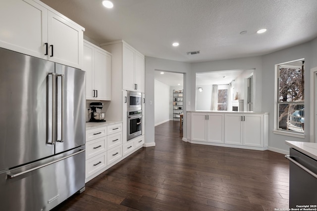 kitchen featuring dark hardwood / wood-style floors, appliances with stainless steel finishes, white cabinets, and light stone countertops