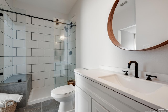 bathroom featuring tile patterned floors, tiled shower, vanity, and toilet