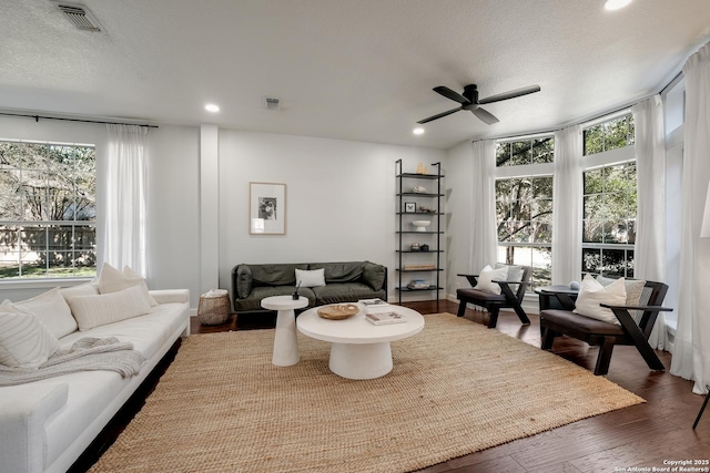 living room featuring a textured ceiling, expansive windows, dark hardwood / wood-style floors, and ceiling fan