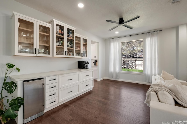 interior space featuring white cabinetry, a textured ceiling, ceiling fan, dark wood-type flooring, and stainless steel refrigerator