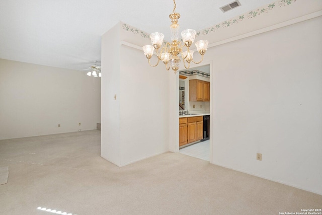 empty room featuring ceiling fan with notable chandelier, a sink, visible vents, and light colored carpet