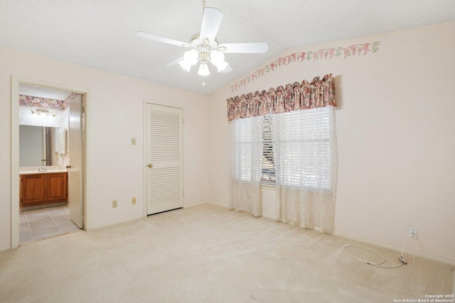 spare room featuring light carpet, ceiling fan, vaulted ceiling, and a sink