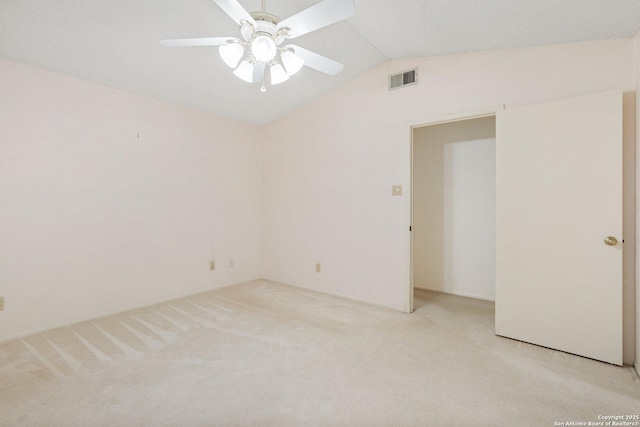 spare room with lofted ceiling, light carpet, ceiling fan, and visible vents