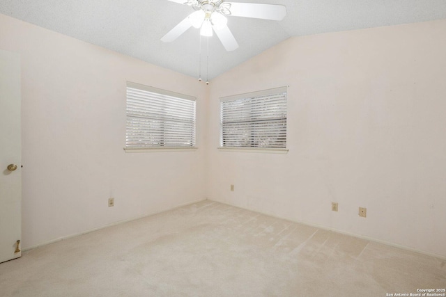 empty room featuring lofted ceiling, light carpet, and a ceiling fan