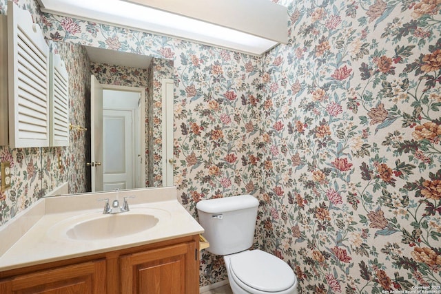 bathroom featuring vanity, toilet, and wallpapered walls