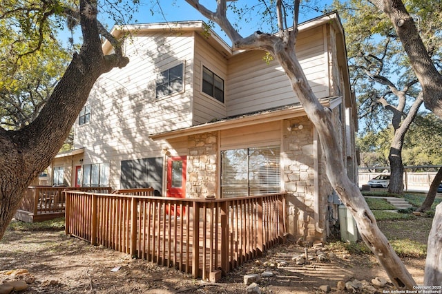 rear view of house featuring stone siding and a deck