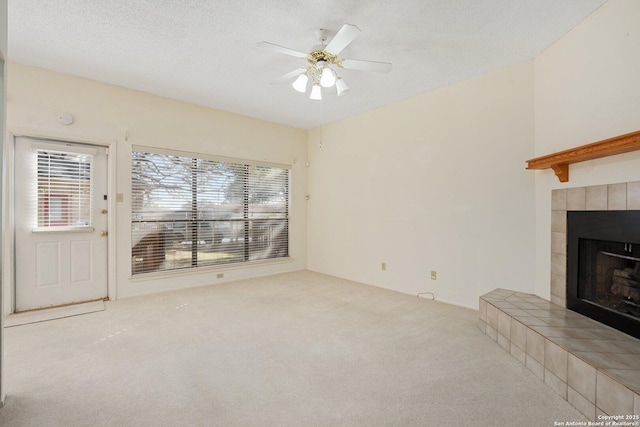 unfurnished living room featuring a textured ceiling, carpet floors, ceiling fan, and a fireplace