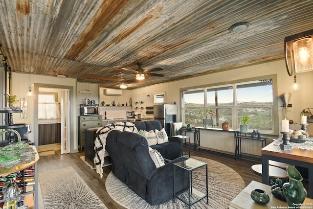 living area with a ceiling fan, an AC wall unit, and wood finished floors