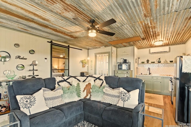 living room featuring a barn door, wooden ceiling, a ceiling fan, a wall mounted AC, and light wood-type flooring